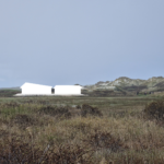Figuur van het Delta Shelter gebouw in het landschap te zien vanuit het oosten